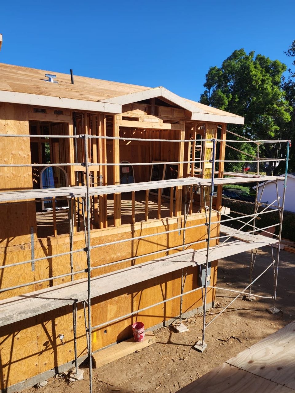 Two-story gable-end framing with plywood sheathing and scaffolding on a custom residential build in Los Angeles — PBG.