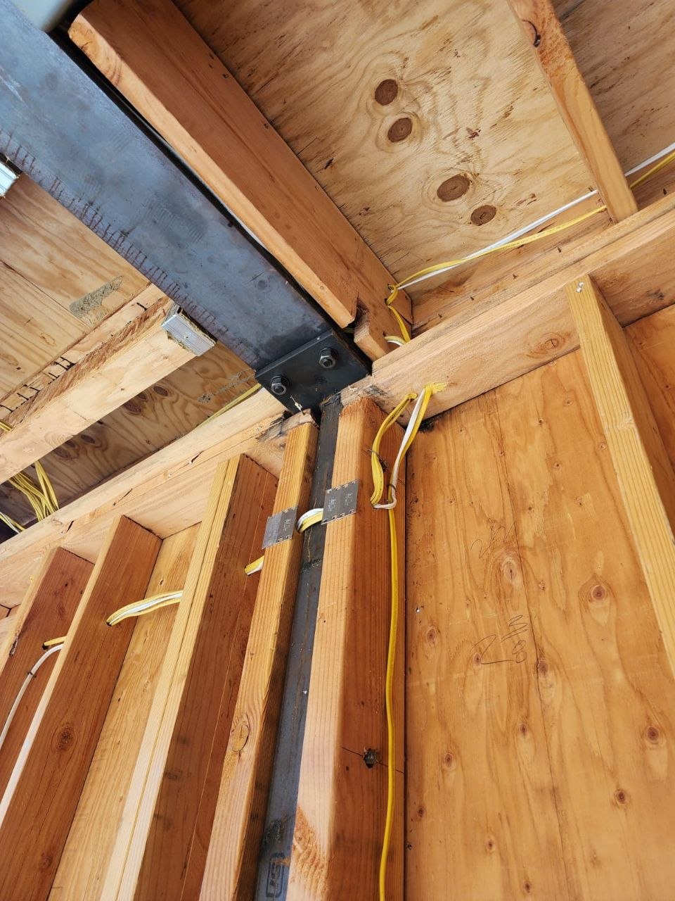 Steel-to-wood moment connection with through-bolts, welded plate, and Simpson strap ties — structural framing detail from a custom PBG build, Los Angeles.