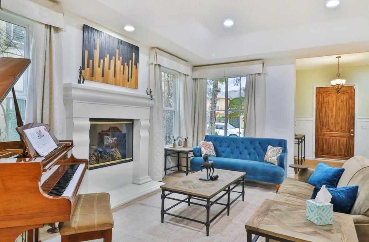 Open-plan living room with tray ceiling, curved staircase, and dining room beyond — finished interior by PBG, Los Angeles residential.