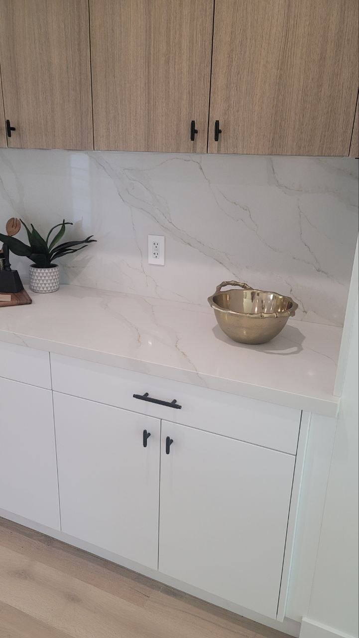 Modern coffee bar — Calacatta-vein quartz backsplash and countertop with matte-black hardware, brass accent bowl, in a PBG custom residential kitchen, Los Angeles.