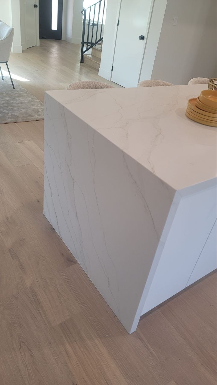 Waterfall-edge island with mitered Calacatta-vein quartz on a modern kitchen — PBG custom residential build, Los Angeles.
