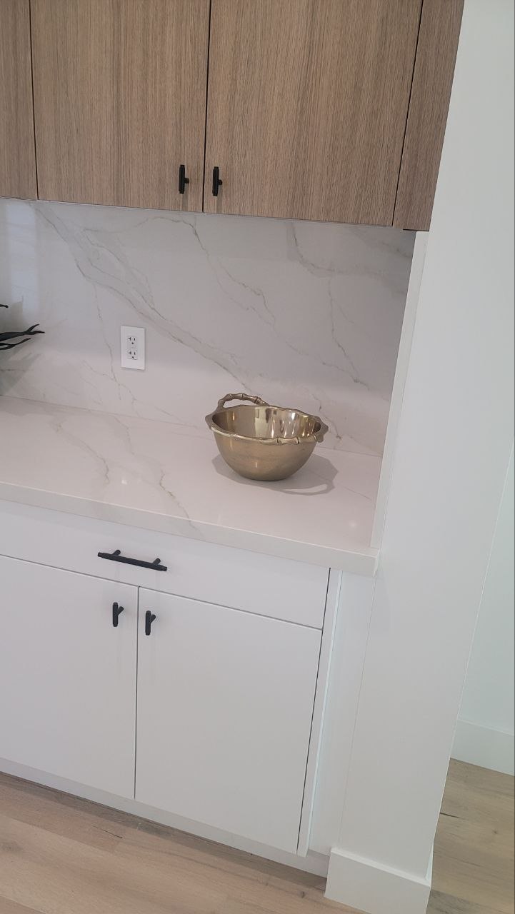 Coffee bar corner vignette — Calacatta-vein quartz backsplash, matte-black hardware, brass bowl accent — PBG custom residential kitchen, Los Angeles.