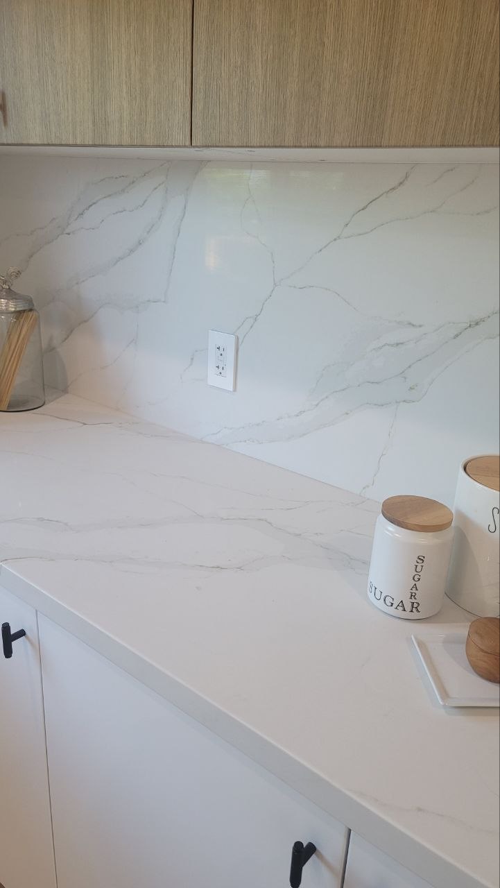 Coffee-bar corner — full-height Calacatta quartz slab backsplash, brass bowl on white cabinetry — PBG custom kitchen, Los Angeles.