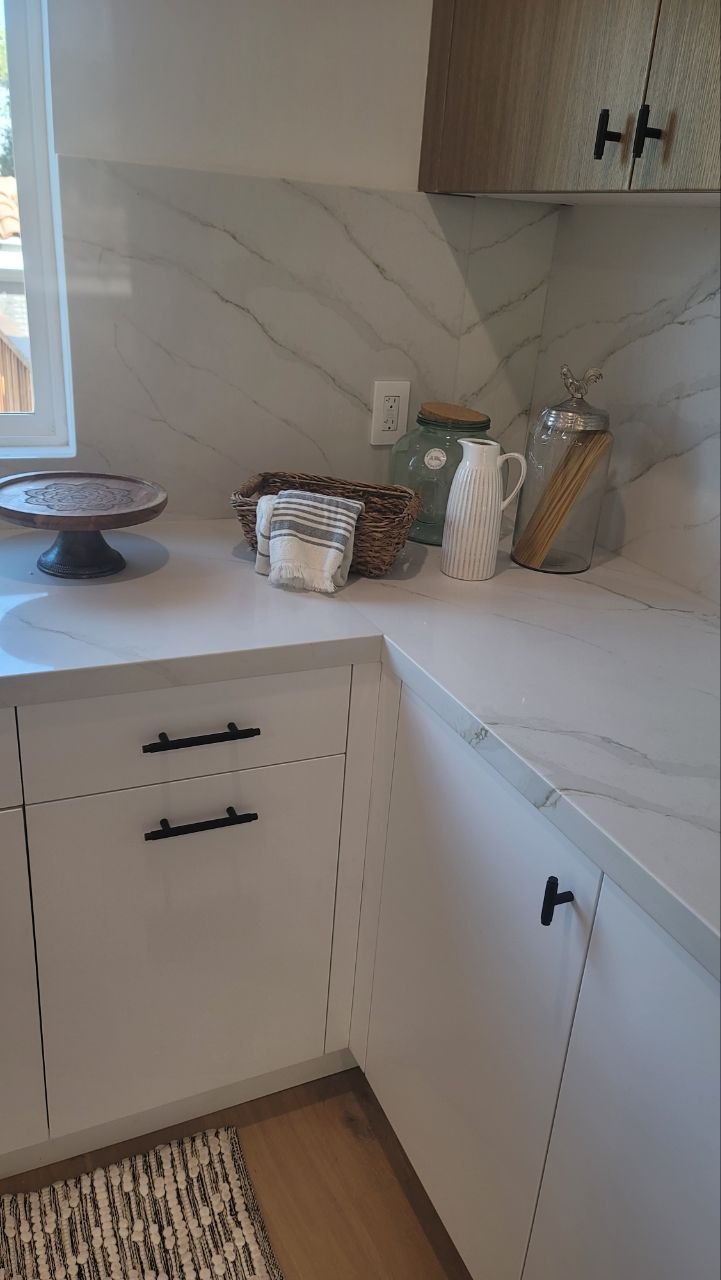 Modern kitchen pantry corner — matte-white flat-panel lowers, light-oak upper, full-height Calacatta slab counter and backsplash, matte-black T-bar hardware — PBG custom kitchen, Los Angeles.