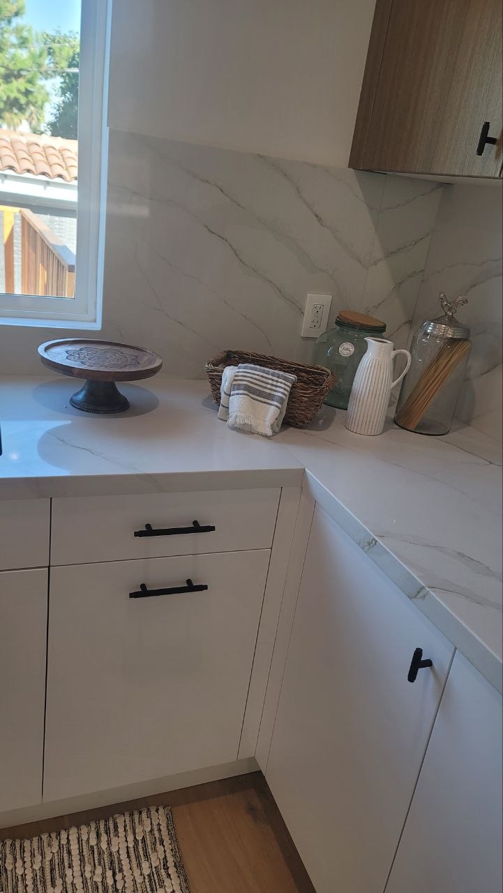 Modern kitchen pantry corner showing Spanish clay barrel-tile roof through window — Calacatta slab surfaces and light-oak upper — PBG custom home, Los Angeles.