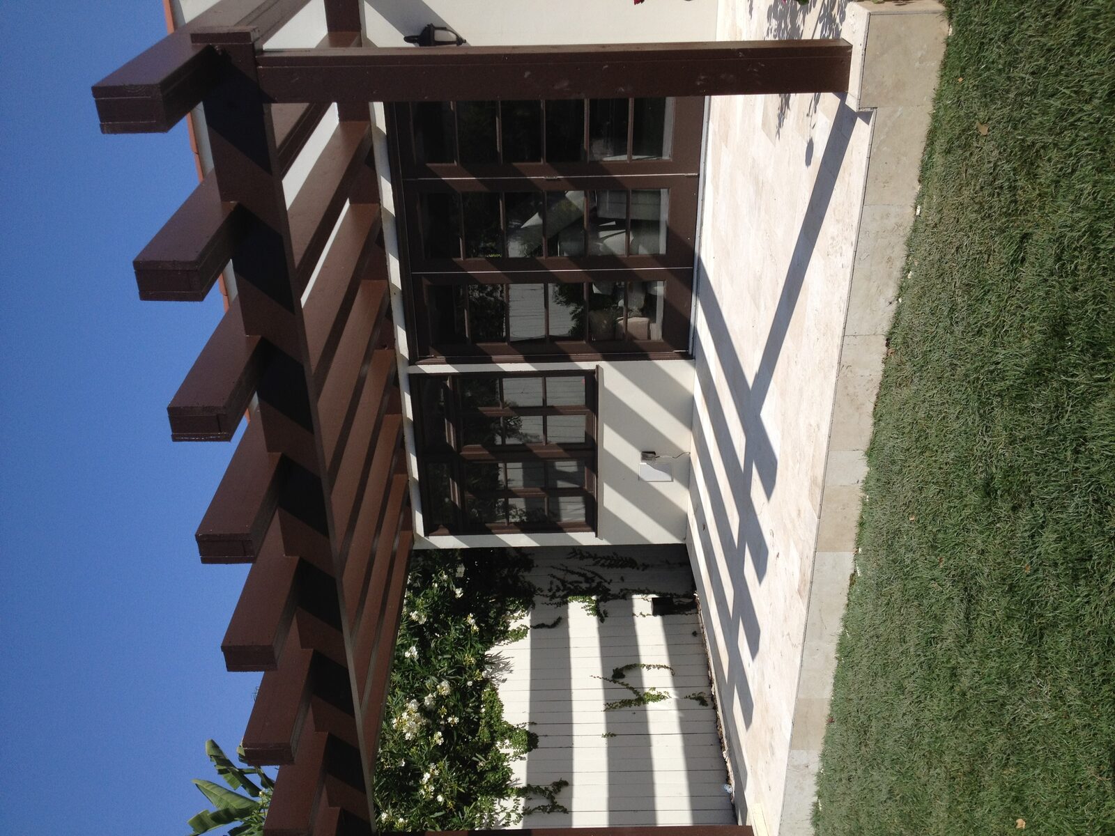 Dark-stained wood pergola over travertine patio — luxury outdoor living by PBG, Los Angeles residential.