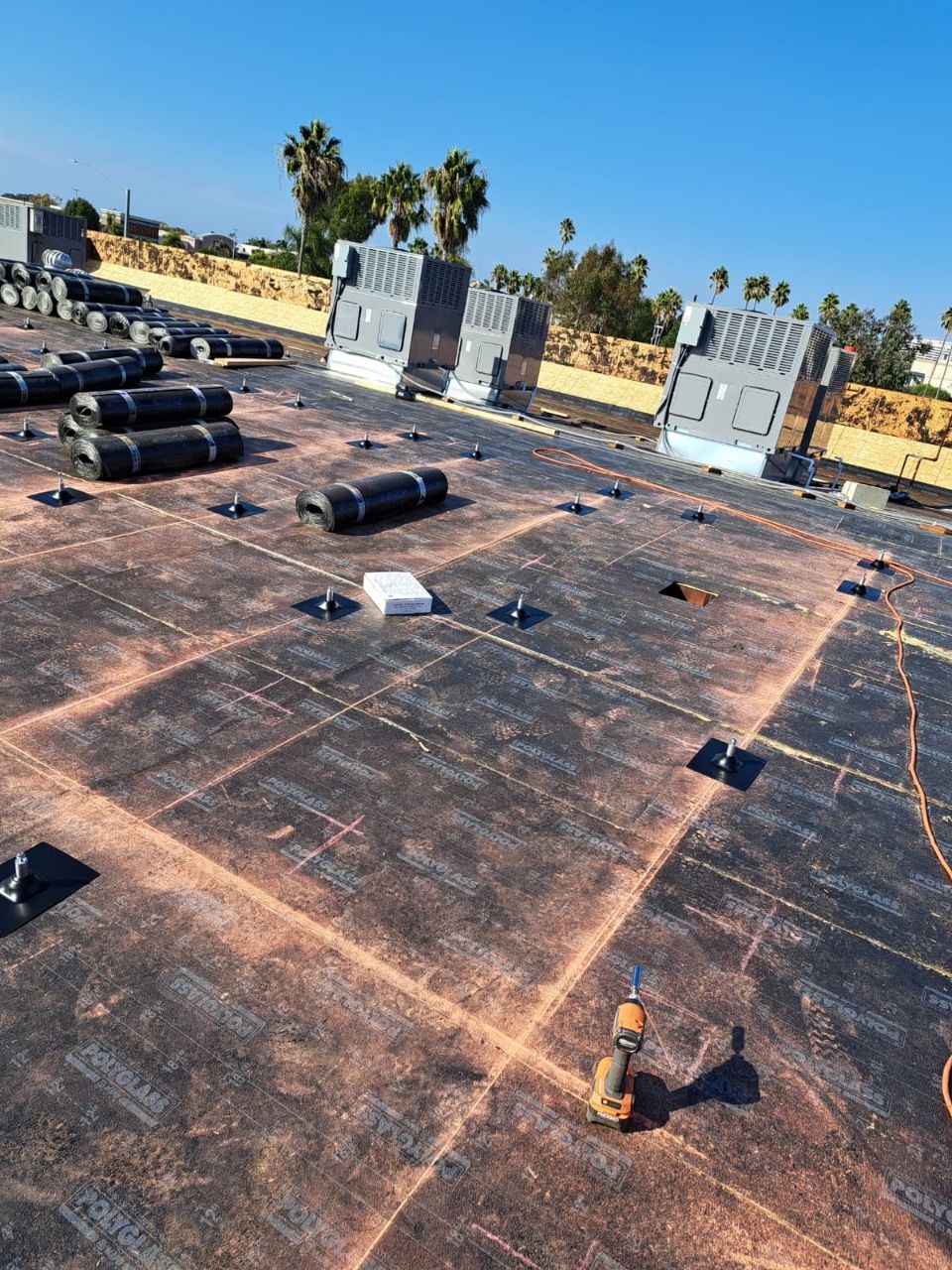 Polyglass base sheet installed around rooftop HVAC penetrations with fastener pattern visible — process detail from a PBG commercial roofing project.