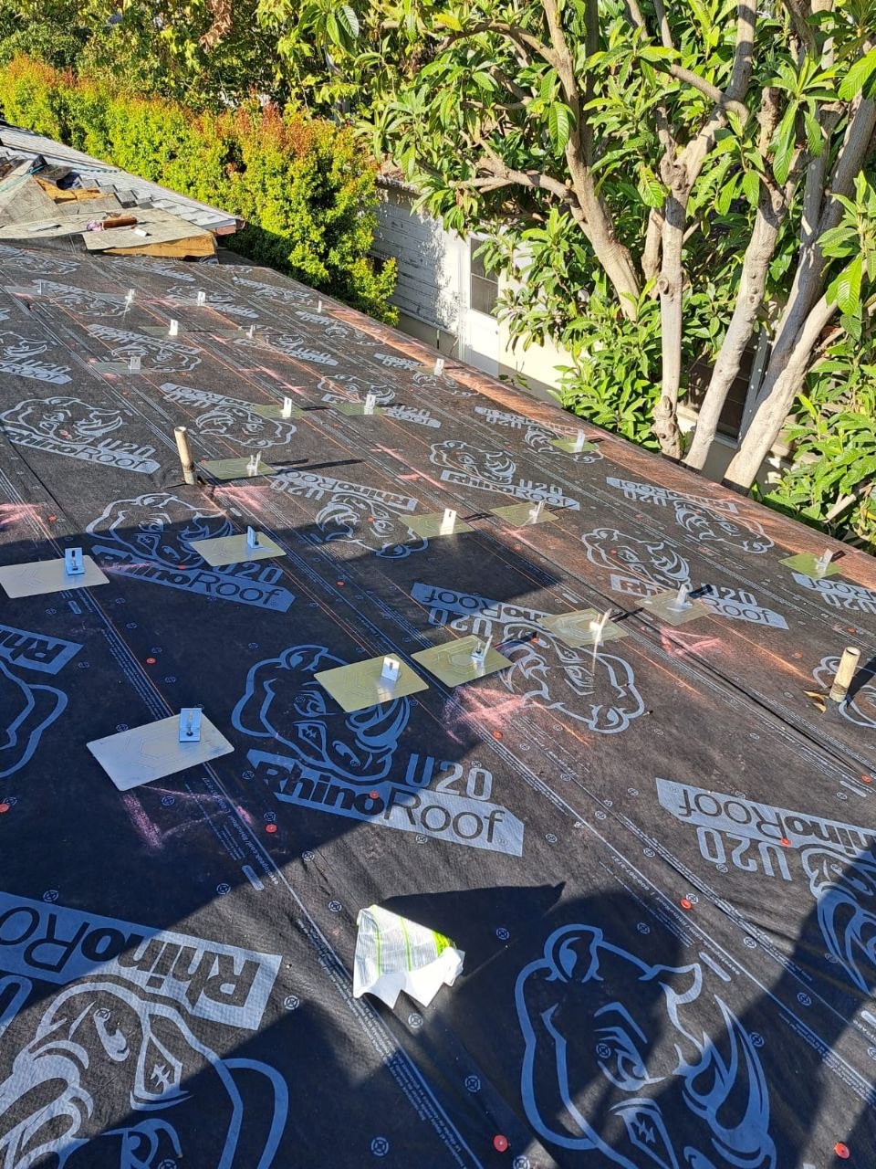 RhinoRoof U20 synthetic underlayment installed with tile-batten hooks staged for tile-course install — wide view showing neighborhood context and staged FlashKit Pro materials — PBG residential re-roof, Los Angeles.