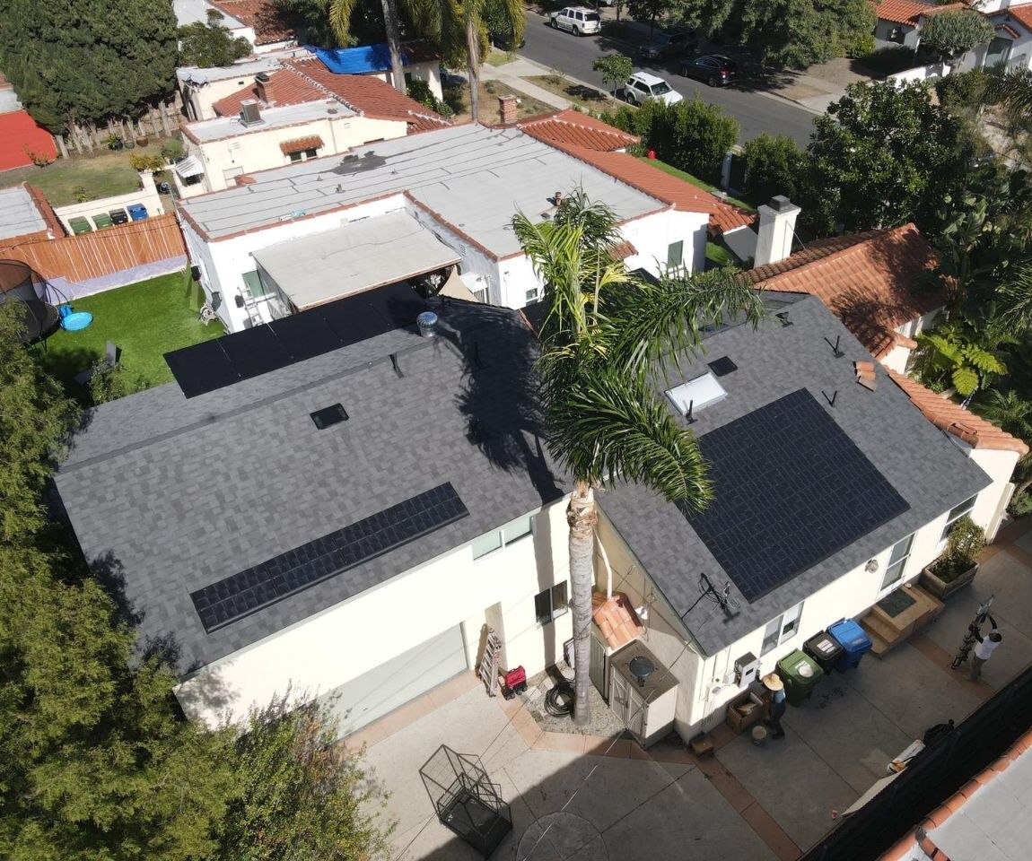 Aerial view of dual solar arrays on a residence with Spanish-style neighborhood context — solar-integrated build by PBG, Los Angeles.