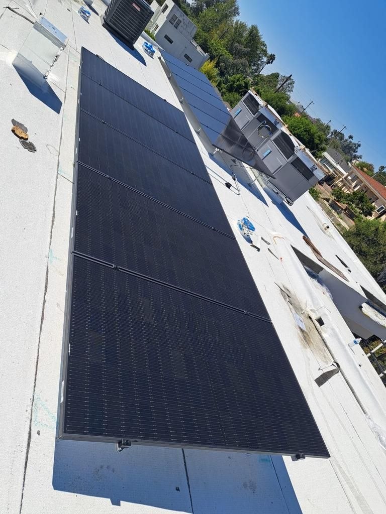 Clean black-on-black solar array on white flat roof adjacent to HVAC — PBG solar install, Los Angeles.