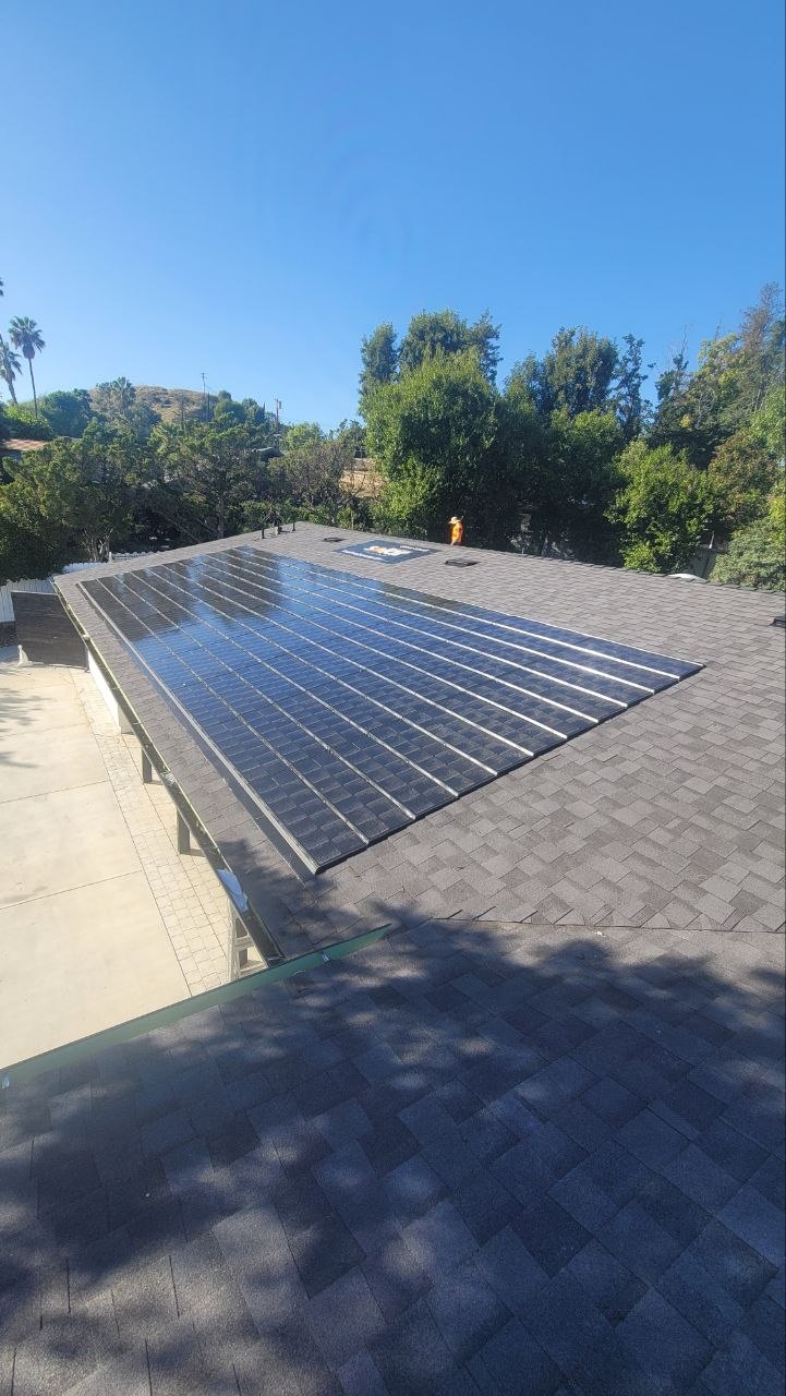 Black solar panels flush-mounted on charcoal asphalt-shingle pitched roof — PBG solar install.