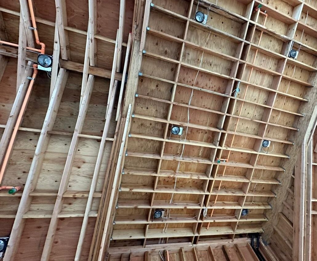 Cathedral ceiling vault — engineered rafters, plywood decking, copper plumbing runs, and recessed lighting rough-in integrated into the structural envelope of a PBG custom residential build, Los Angeles.